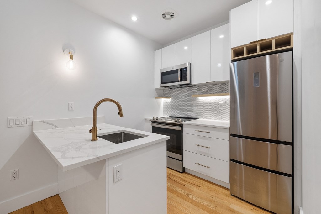 a kitchen with white cabinets and a stainless steel refrigerator